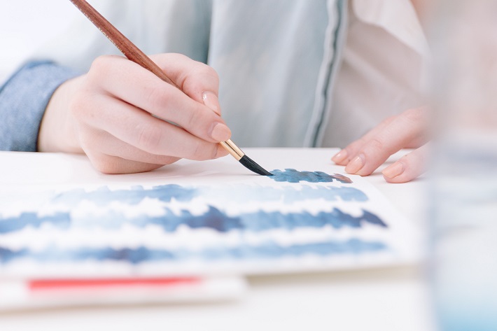 A lady experimenting with shades of blue during a cruise ship painting class