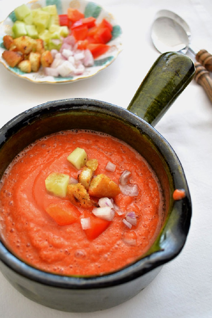 A pan of gazpacho topped with vegetables and bread