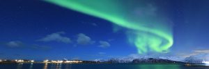 Northern lights shining above mountains and water in Tromso