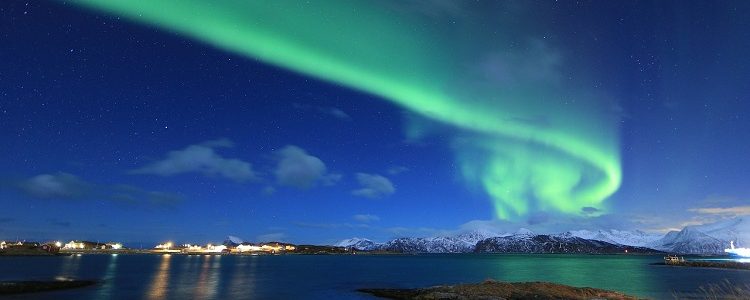 Northern lights shining above mountains and water in Tromso