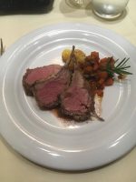 Plate of beef with vegetables and rosemary on-board MSC Meraviglia