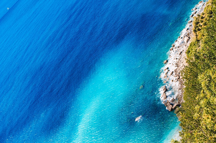 Bright blue sea lapping onto a lush shoreline in the Western Mediterranean