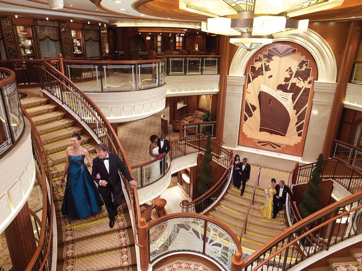 Couple in evening dress descending the grand staircase in Cunard Queen Elizabeth's three-tier lobby