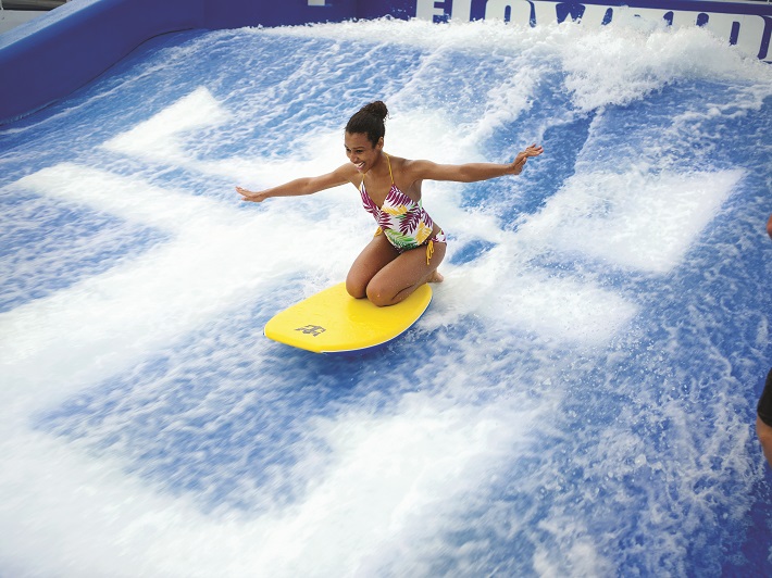 Woman on a yellow surfboard on Independence of the Sea's Flowrider surf simulator