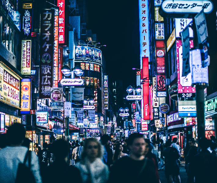 Tourists walking through the neon-lit streets of Tokyo at night