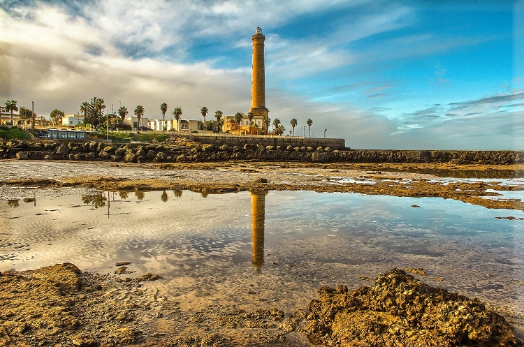 A lighthouse reflected in the wet sand on a beach in Cadiz on the Costa del Sol
