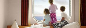 Children gazing out of the window of an outside family stateroom on a Carnival cruise ship